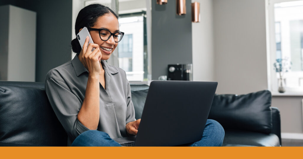 A woman talking on the phone and filling out information on her computer