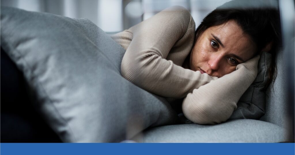 A young woman lies on a couch, filled with anxiety after a recent car wreck.