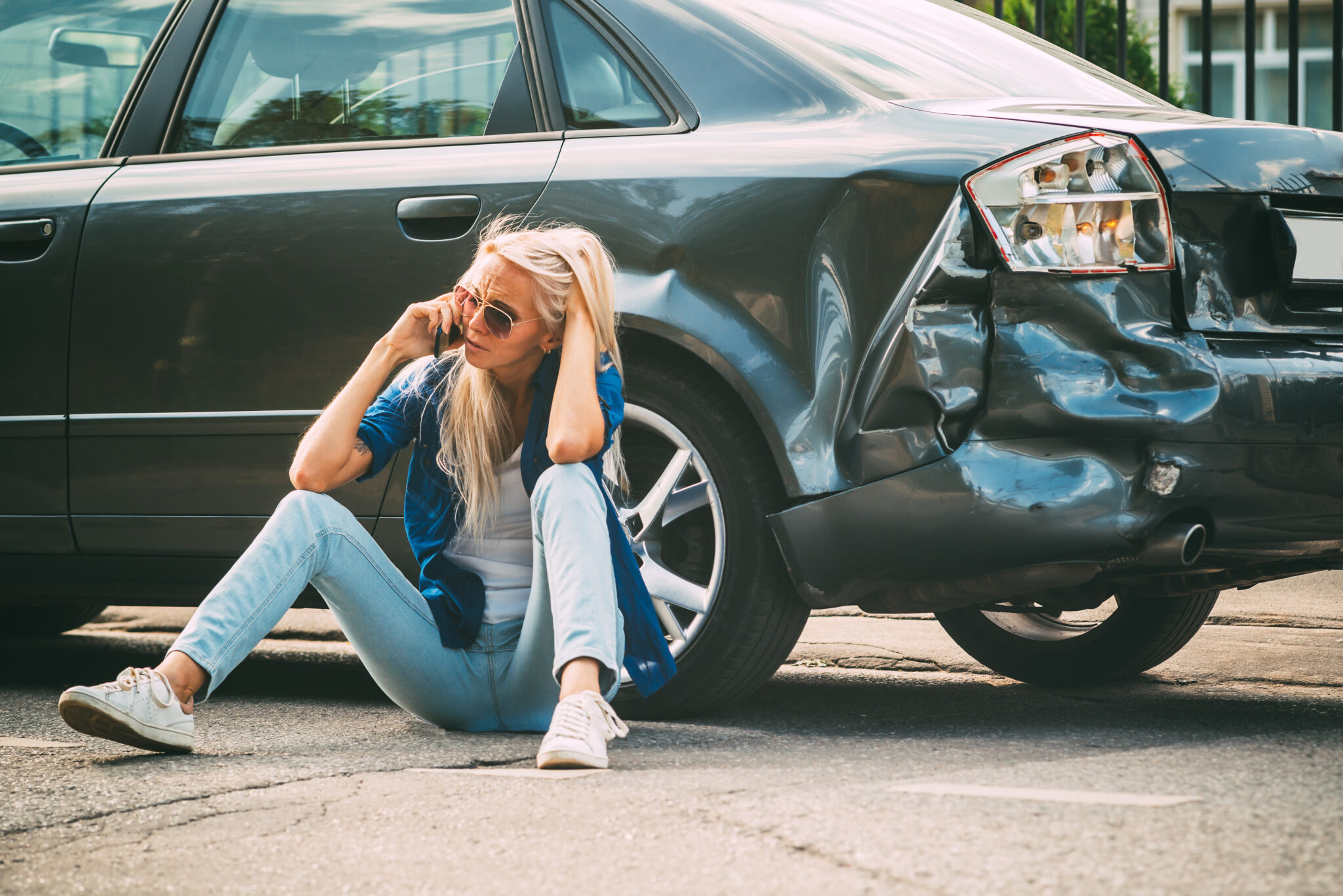 girl sits on the road, near the broken car and calls on the phon