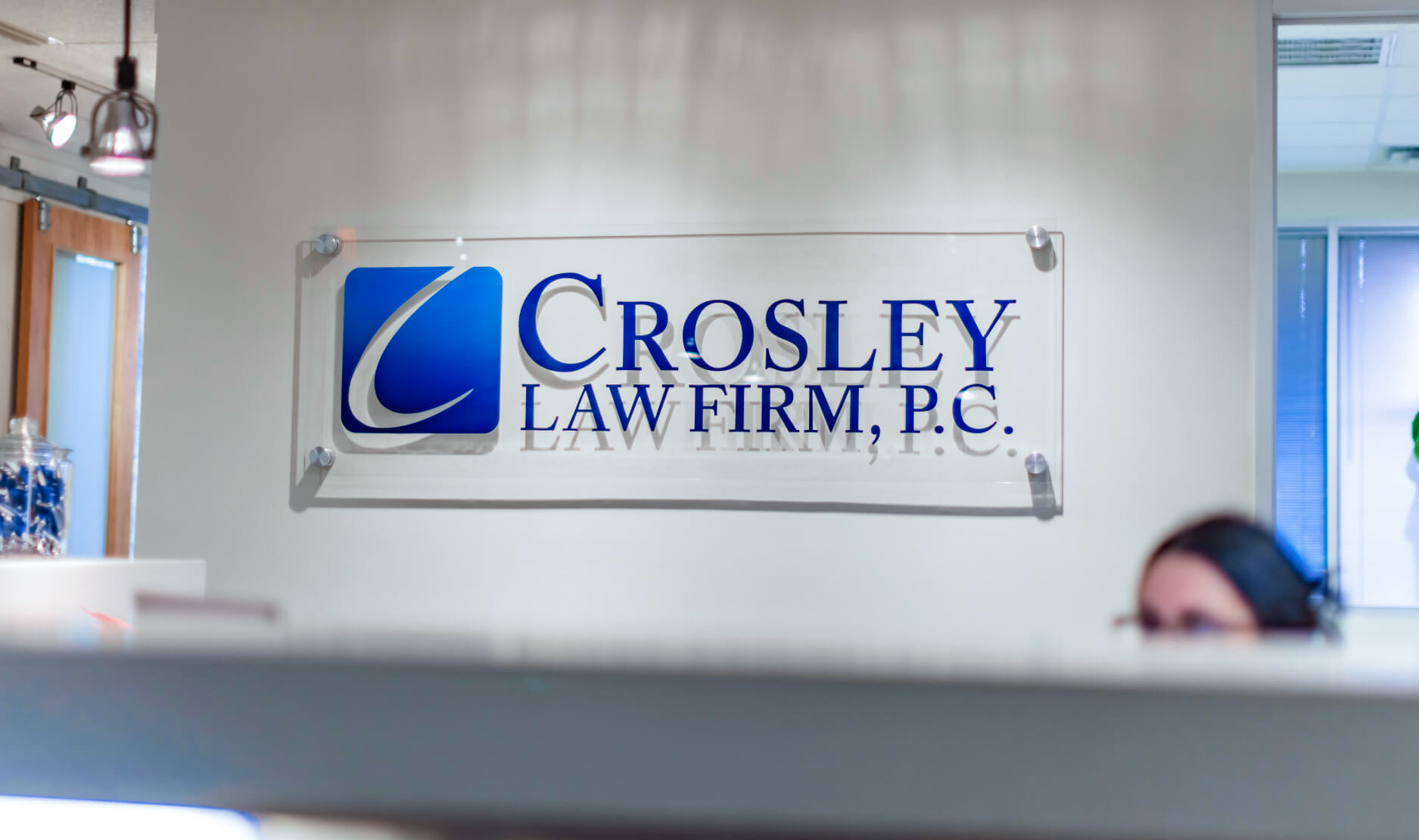 Señalización en vidrio esmerilado de "Crosley Law Firm, P.C." con fondo de oficina.