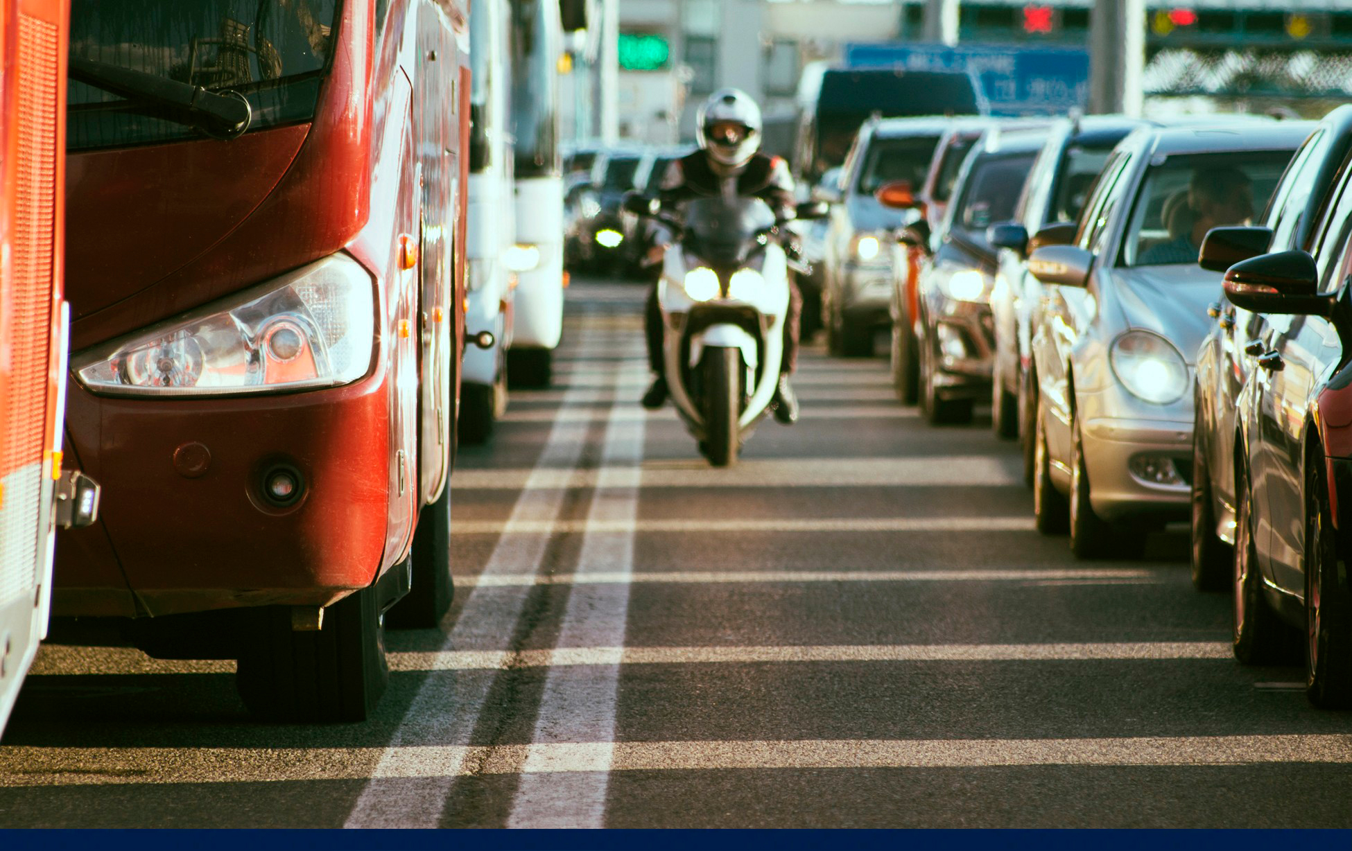 Motorcyclist in helmet lane splitting through heavy urban traffic during daytime