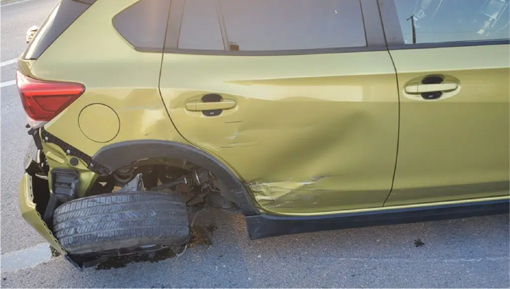 A yellow car with damage on the passenger rear side from a car accident