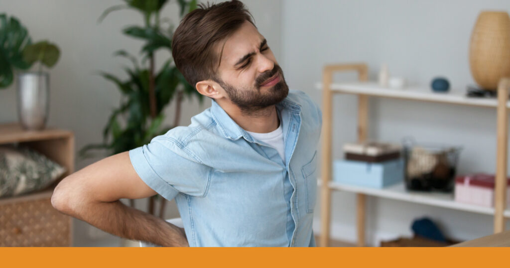 A man clutches his back in pain