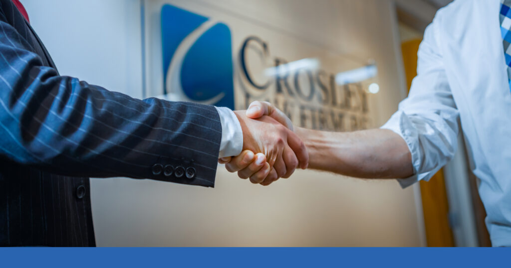 A personal injury attorney shakes hands with a client at the Crosley Law Firm office.