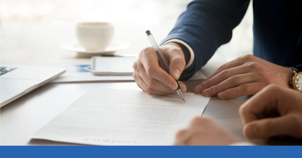 A man in a suit signs a legal document at a personal injury attorney's office