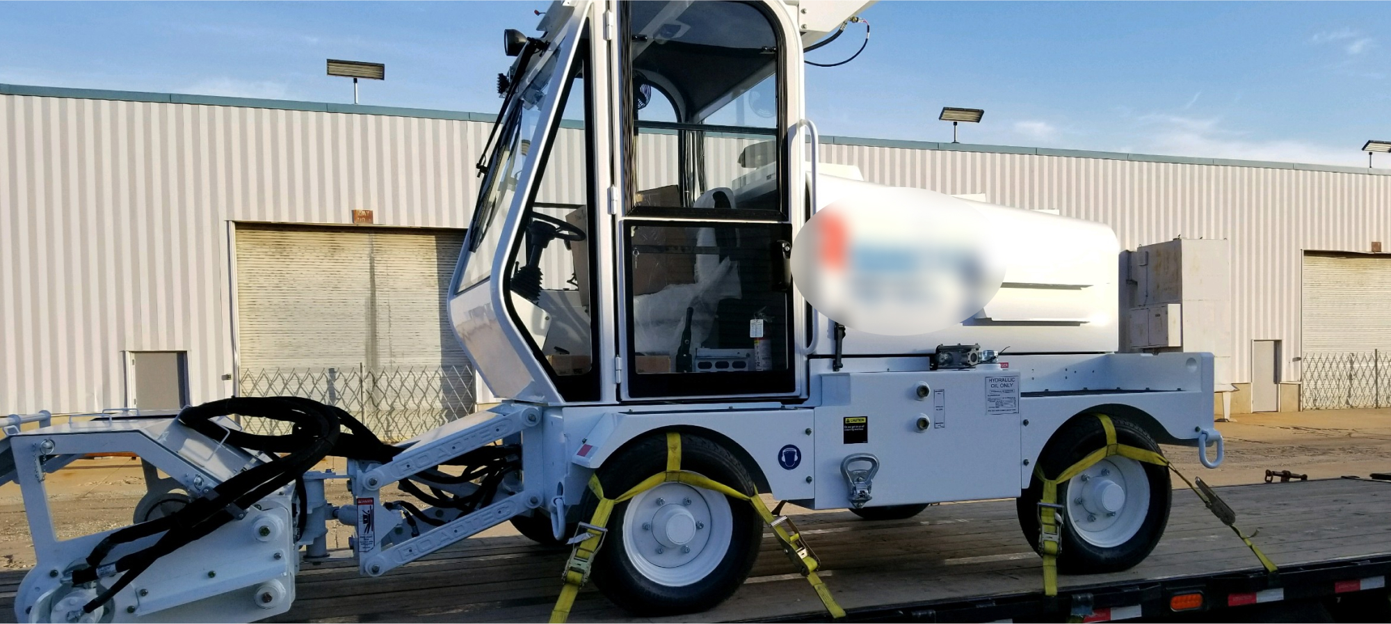 a white street sweeper on a flatbed
