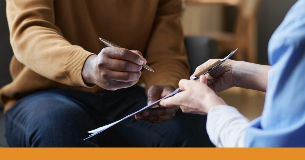A person writes on a clipboard being held by another person