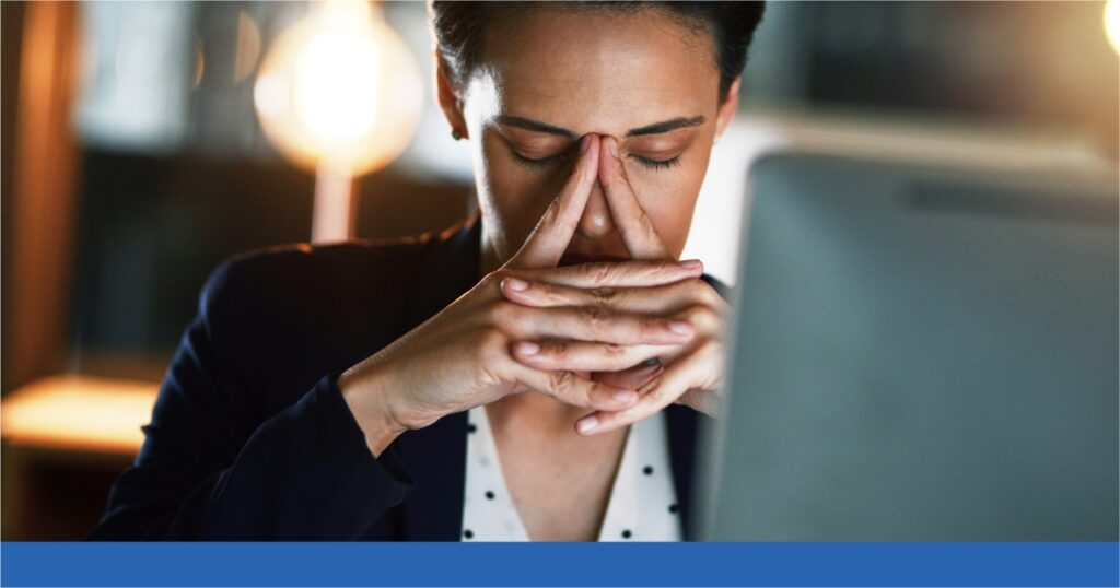 A woman holds her hands in sadness and frustration while working on her laptop.