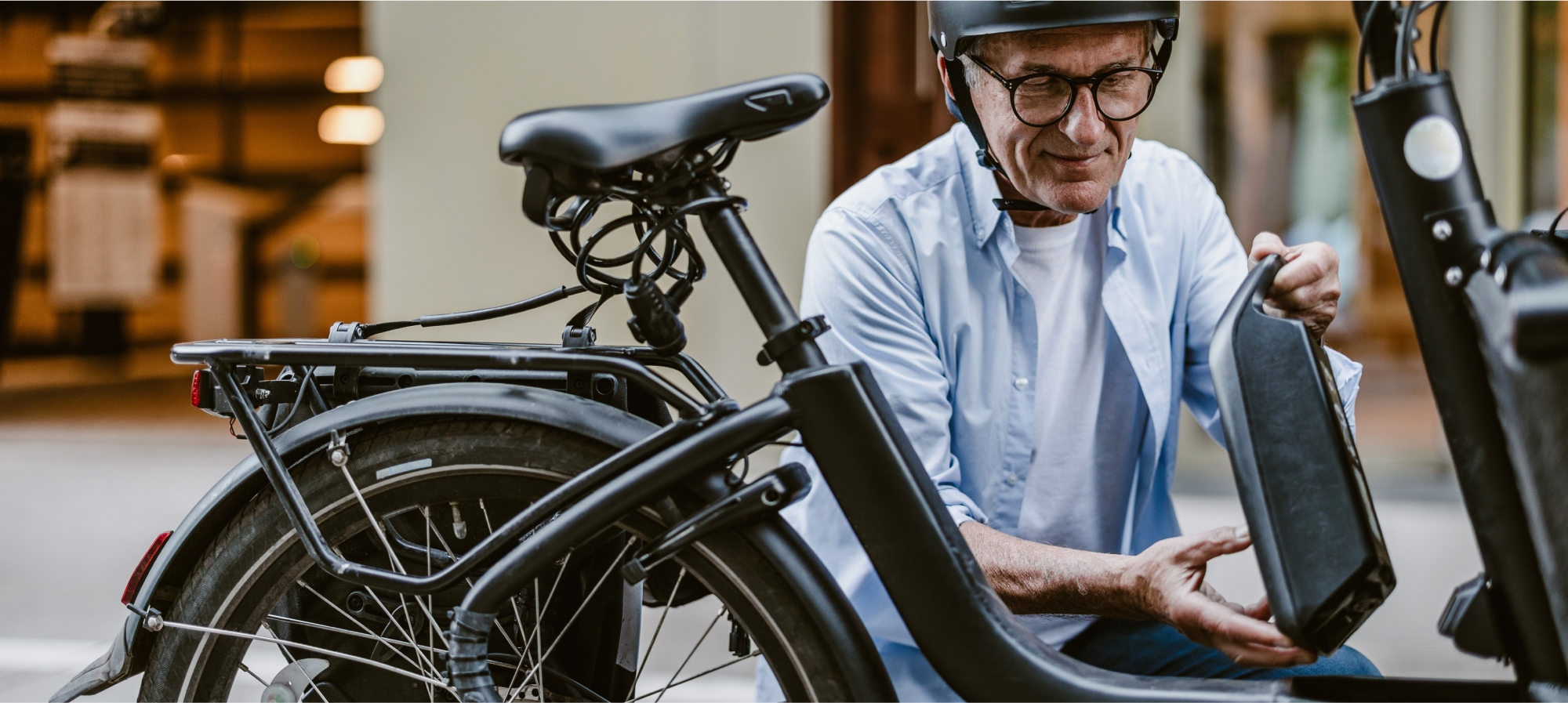 A older adult male changes the battery on his e-bike.