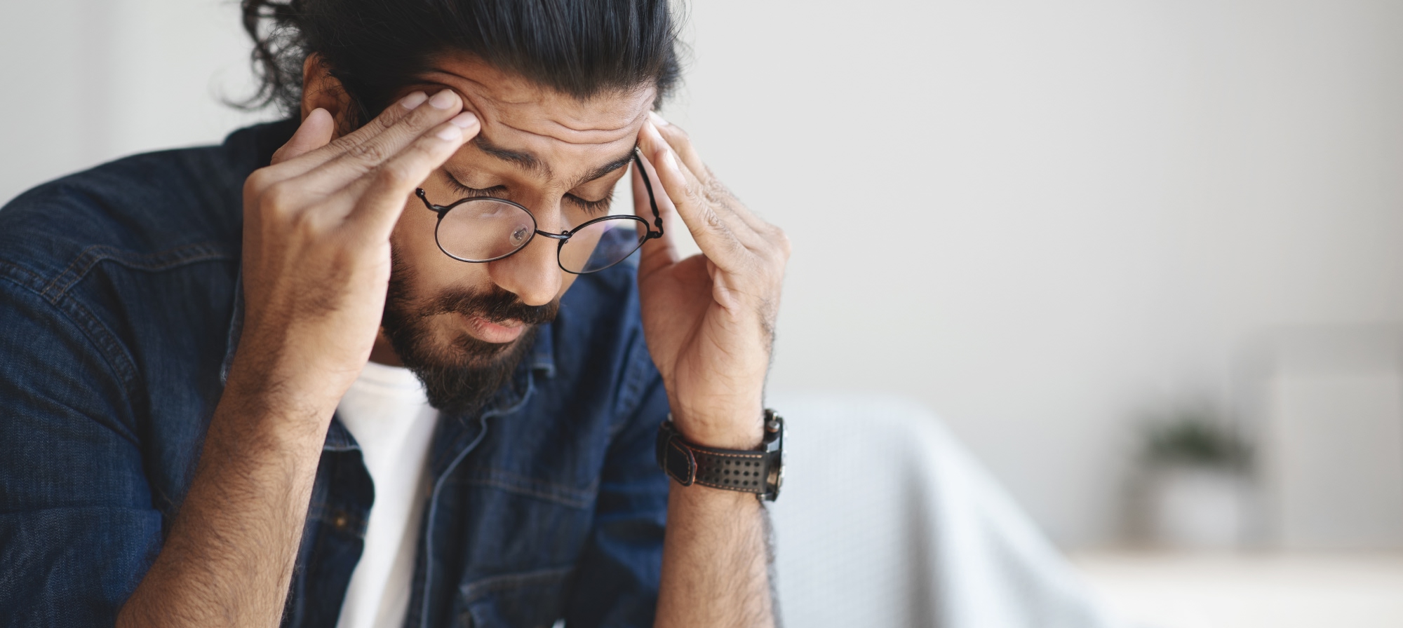 a man with glasses holding his head