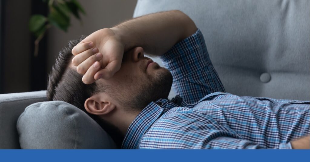 a man lying on a couch with his hand on his face