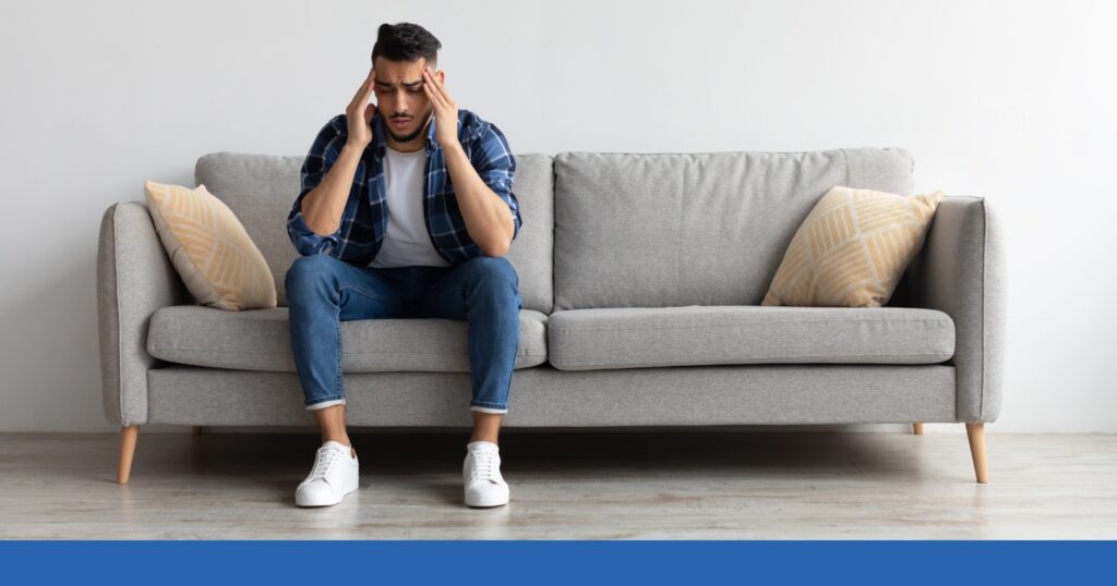 a man sitting on the couch holding his head showing pain after a hit-and-run crash