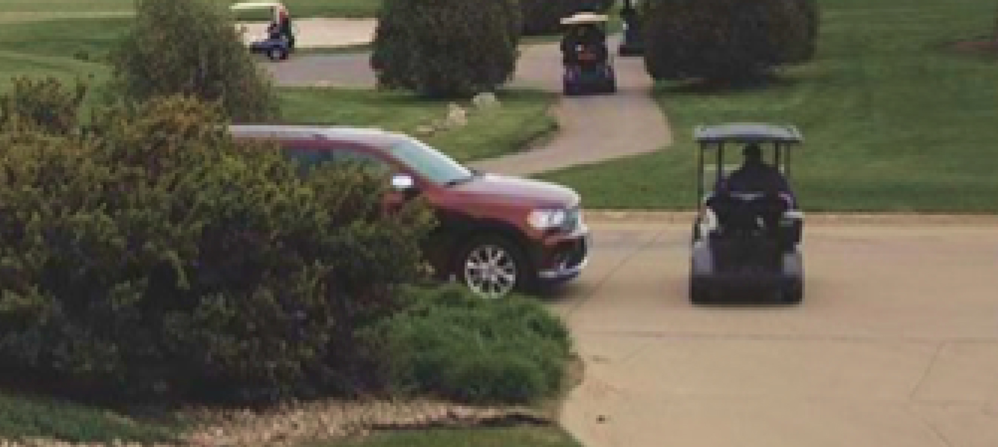 a golf cart driving across the street in front of a vehicle