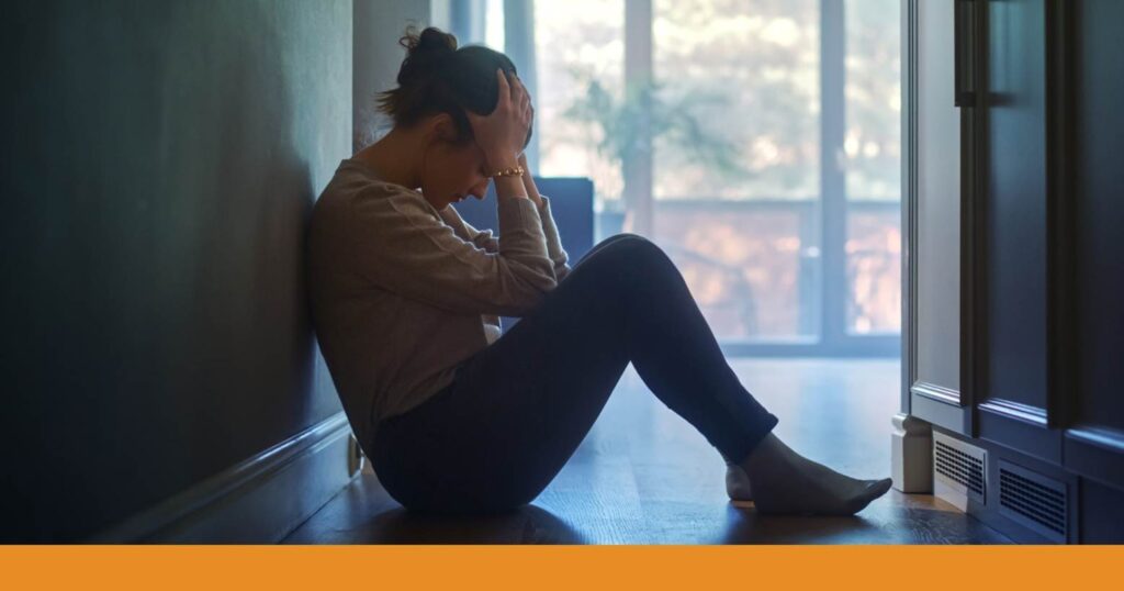 a woman sitting on the floor holding her head and showing pain or frustration