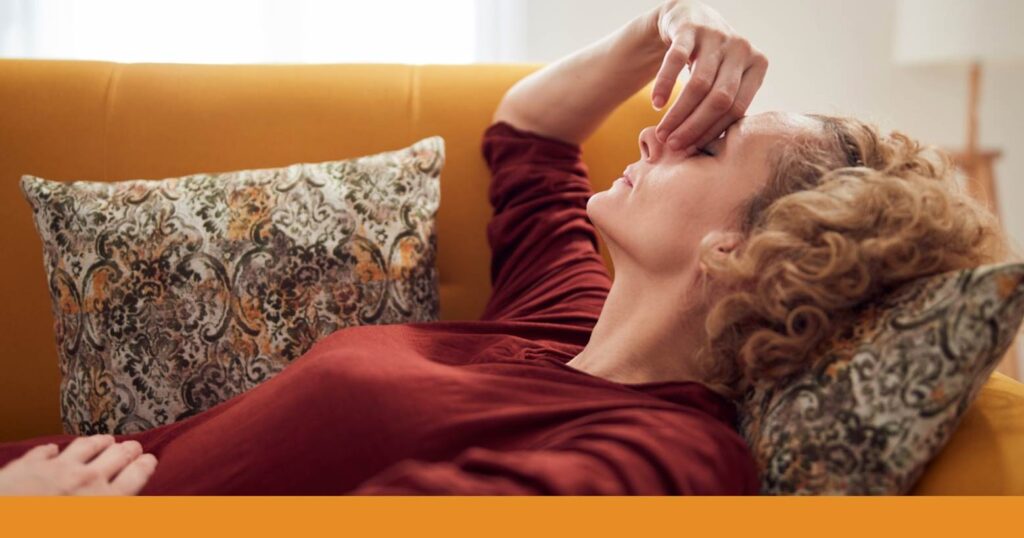 a woman lying on a couch holding her head and face