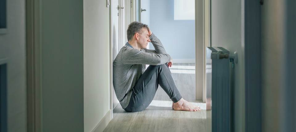 a man sitting on the floor holding his head after a brain injury
