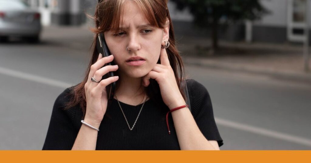 a person on the phone with a concerned expression after a car accident