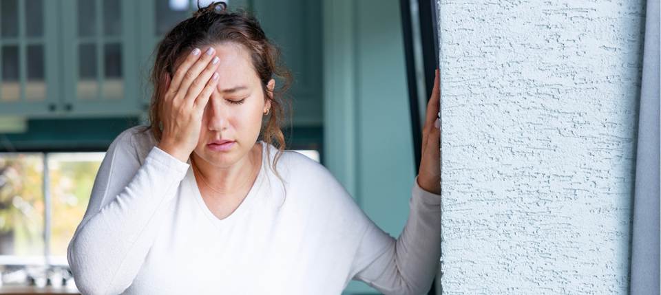 a woman with her hand on her head and her eyes closed from a brain injury