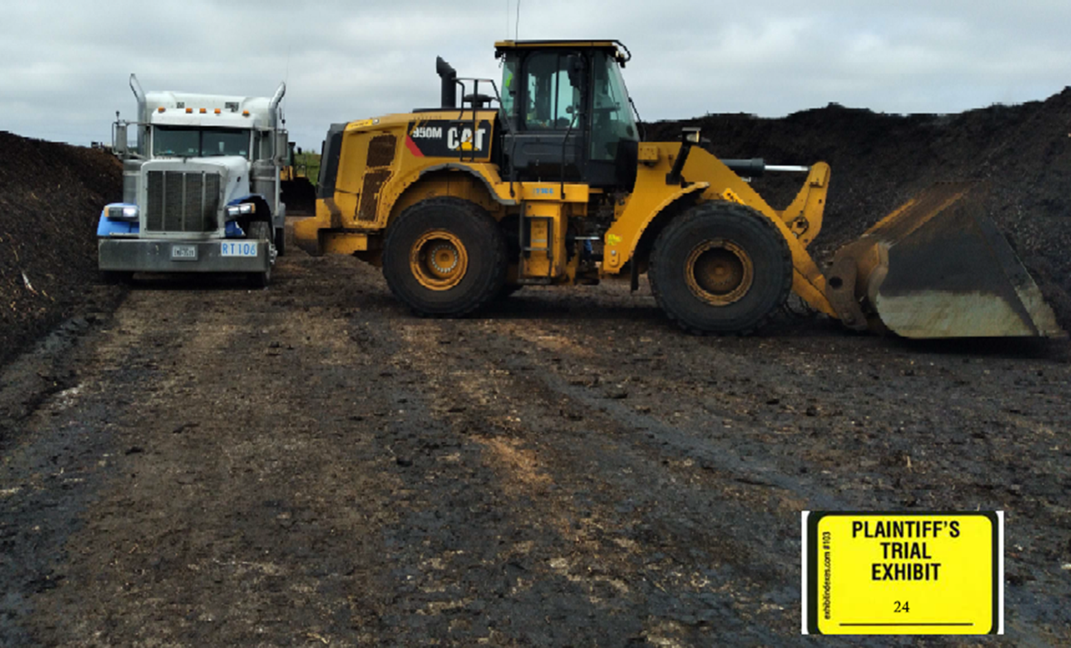 Heavy equipment in a field as part of evidence for a liability case involving a truck accident. The truck is damaged from the heavy machinery that backed into the truck.