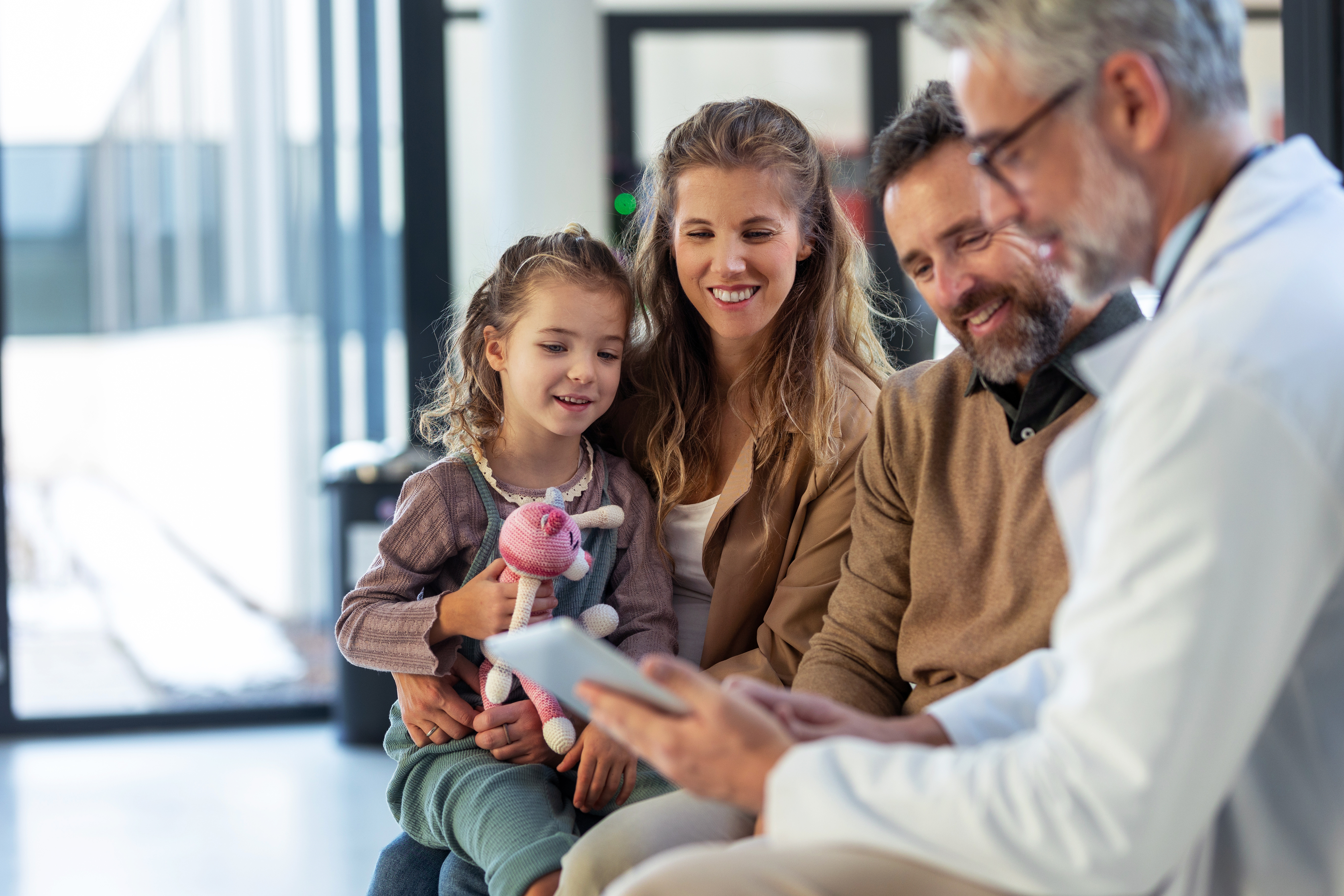 Concussions in toddlers and small children: what parents should know 3 Un pediatra hablando con unos padres y un niño pequeño que sostiene un peluche