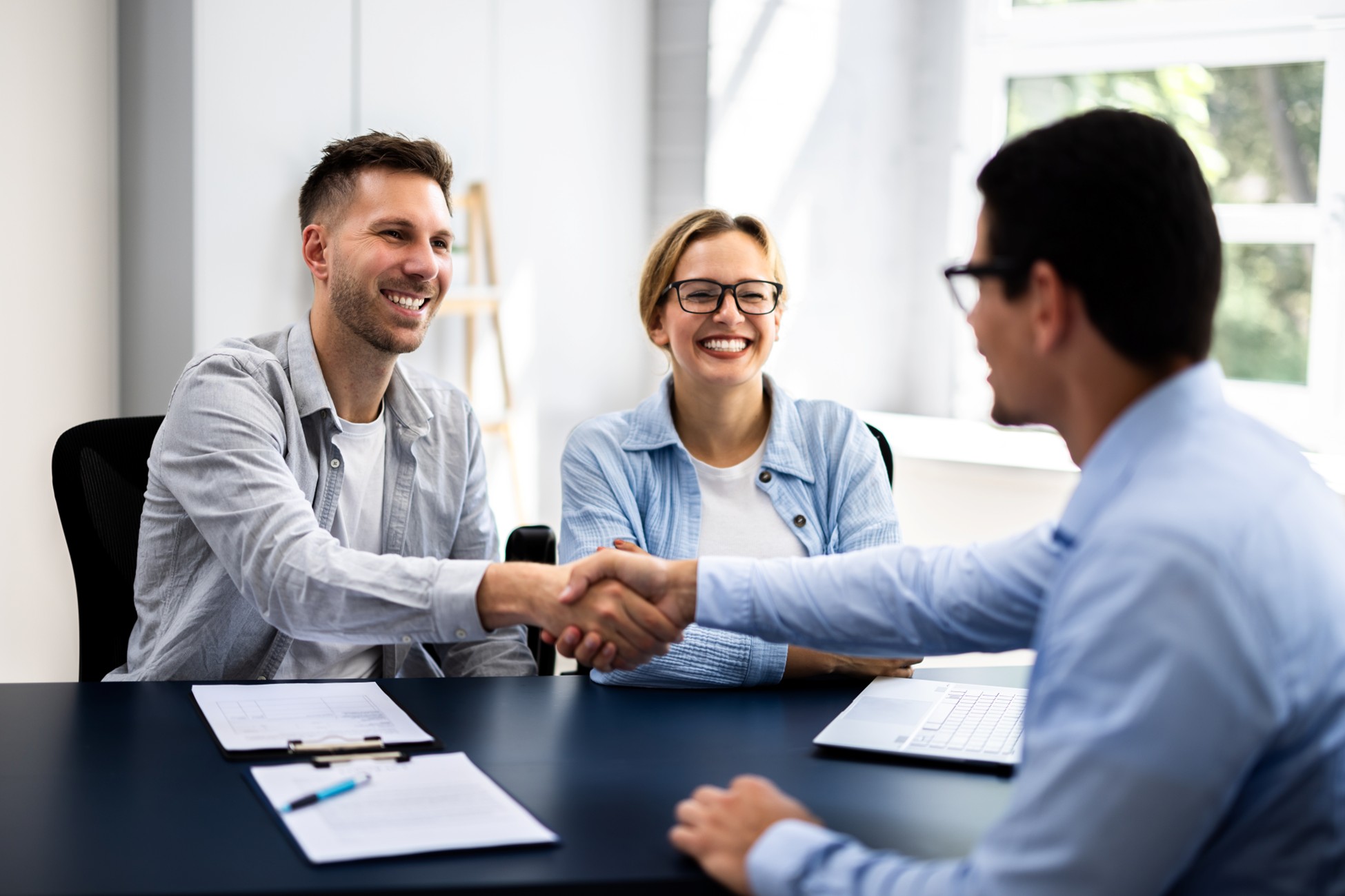Truck accident lawyer shaking hands with smiling clients during a successful case settlement