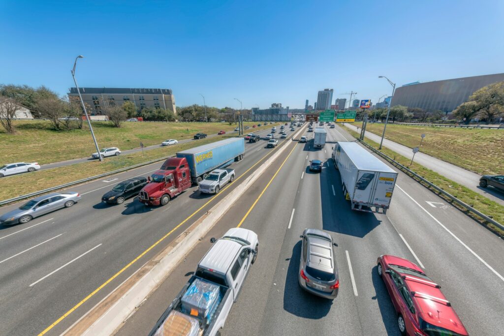 Heavy traffic on Interstate 35 in Texas with commercial trucks and cars in multiple lanes during daytime