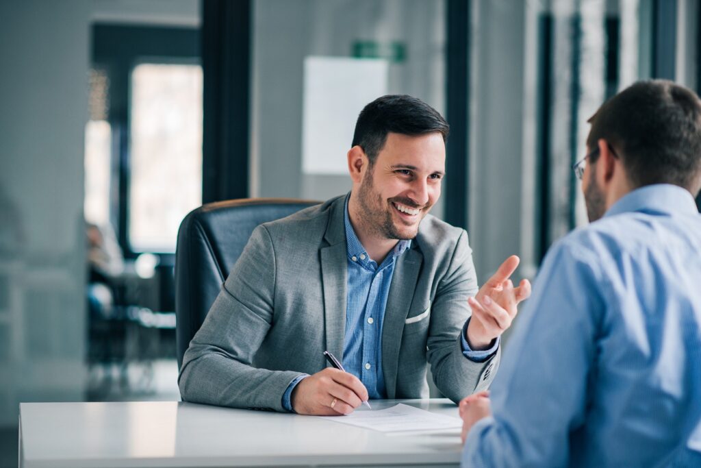 Friendly attorney in gray suit consulting with a client at a desk during a free personal injury consultation