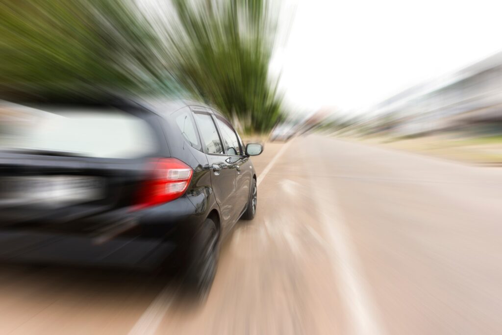 Black car speeding down a road with motion blur conveying reckless driving conditions on Texas highways
