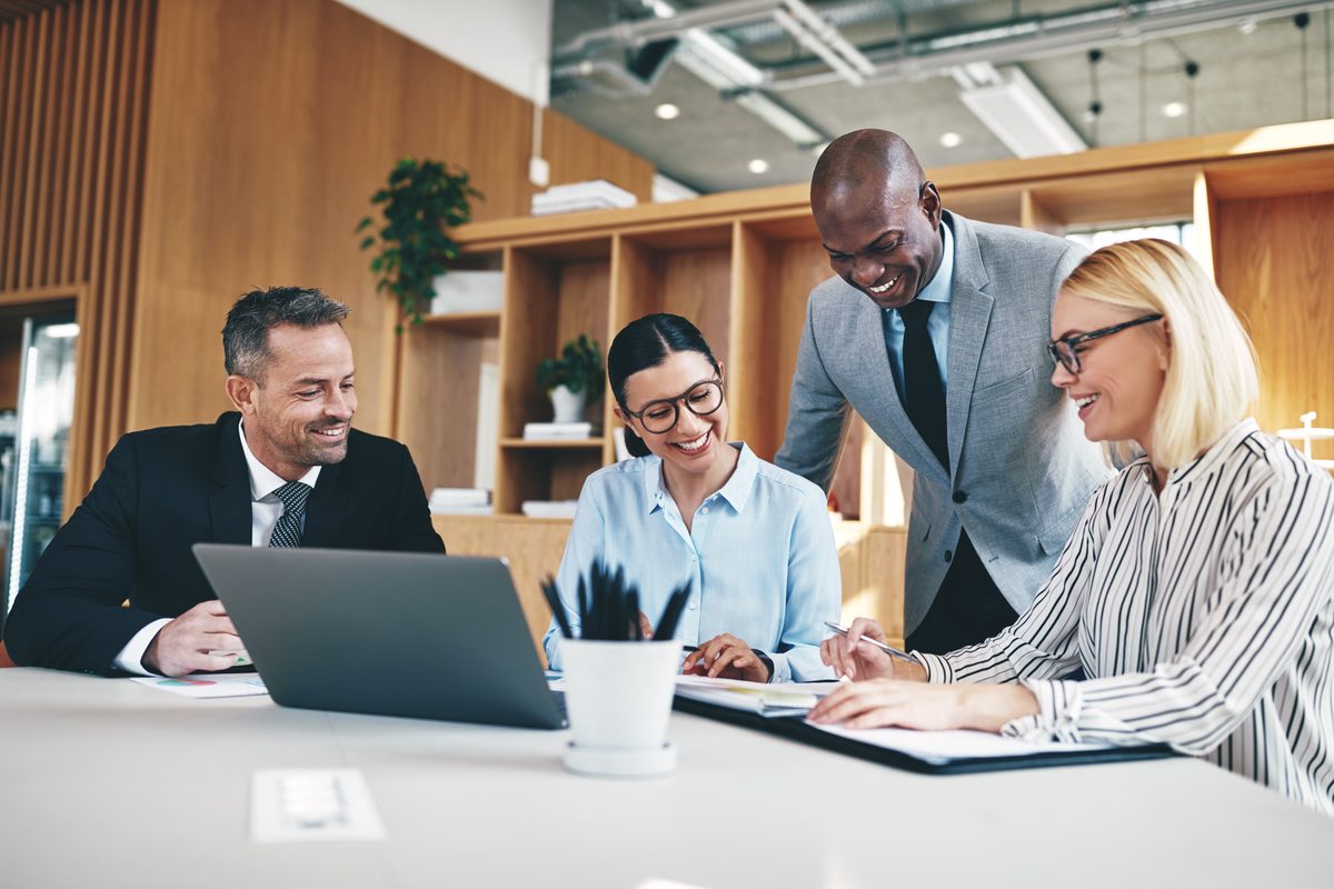 Four smiling legal professionals reviewing case documents together at an office table
