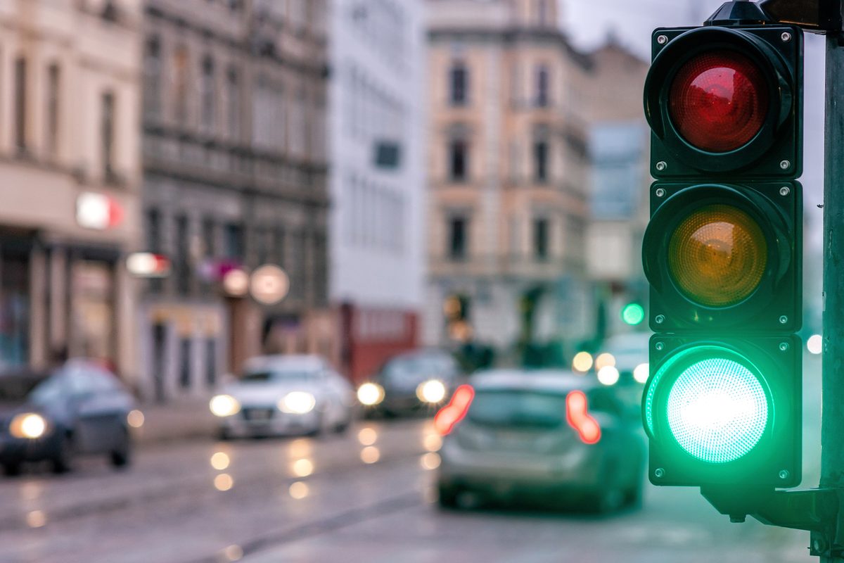 Traffic light glowing green over a busy city street with cars at an intersection