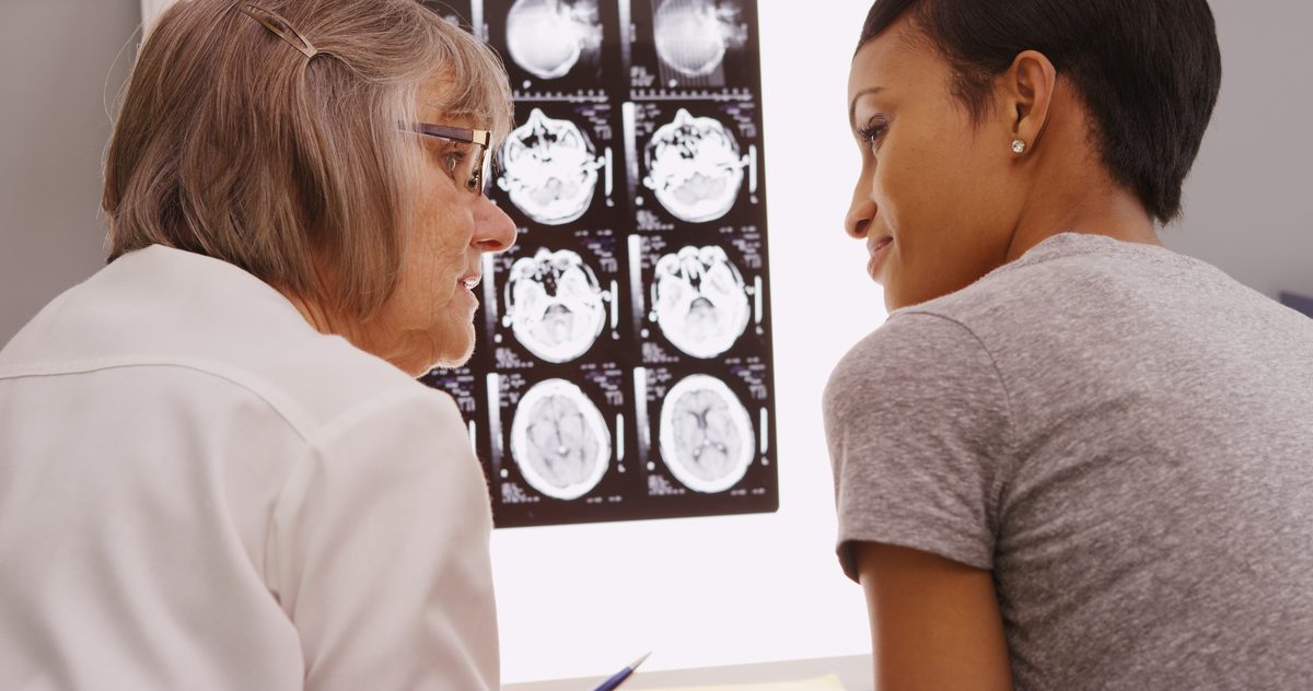 Doctor and patient reviewing brain CT scan images together during a traumatic brain injury evaluation
