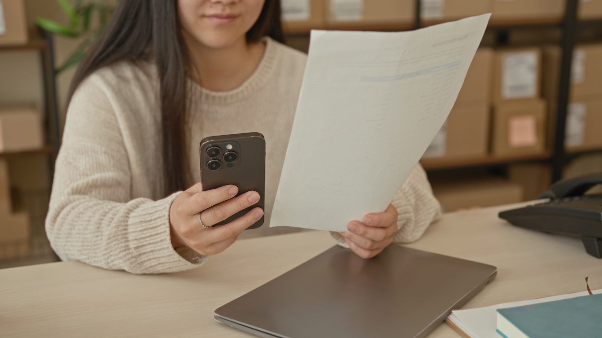 Woman photographing a medical bill statement while reviewing insurance paperwork