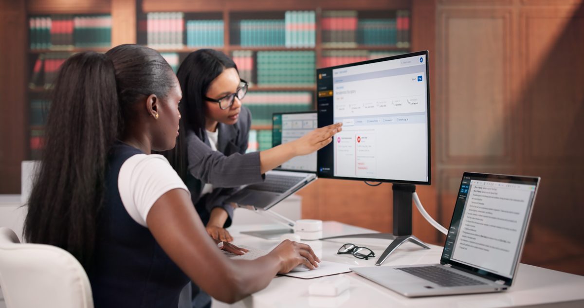 Two legal professionals reviewing a car accident claim file on a computer monitor in a law office