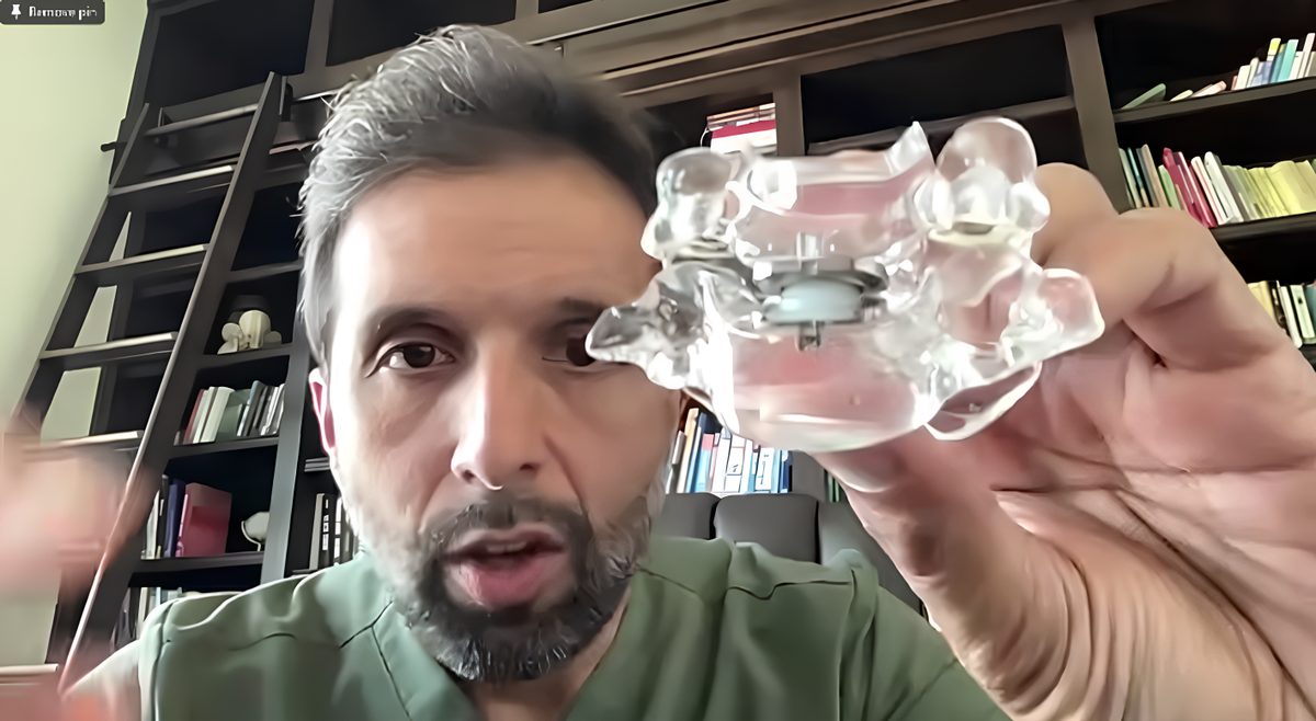 Spine surgeon holding a clear spinal model with an artificial disc implant, like the one used in Ellen’s neck surgery