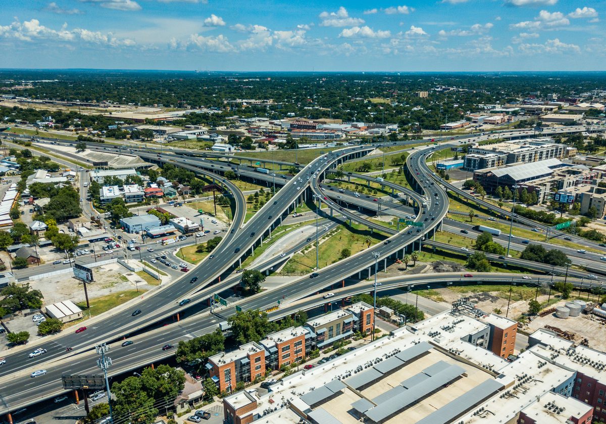 Aerial view of a busy multilevel highway interchange with traffic moving across curving overpasses near a city